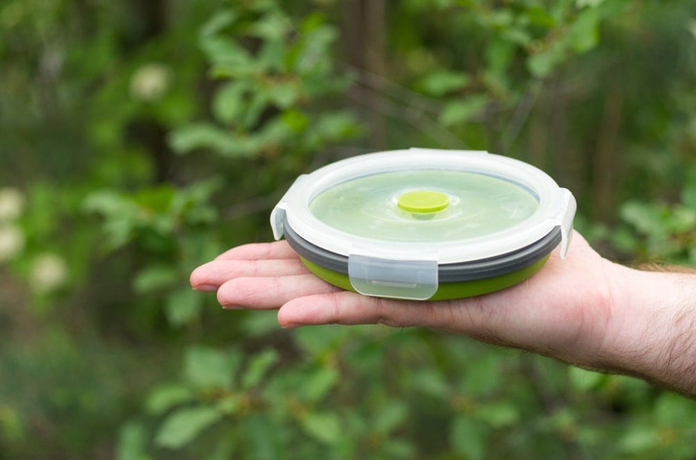 A green container with a lid held by a person
