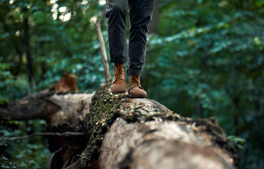 Man with hiking boots walking on a tree