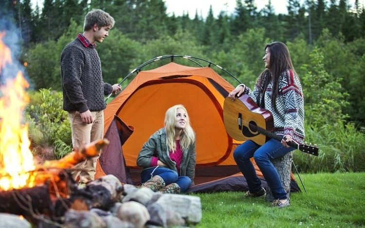 teens playing guitar while camping