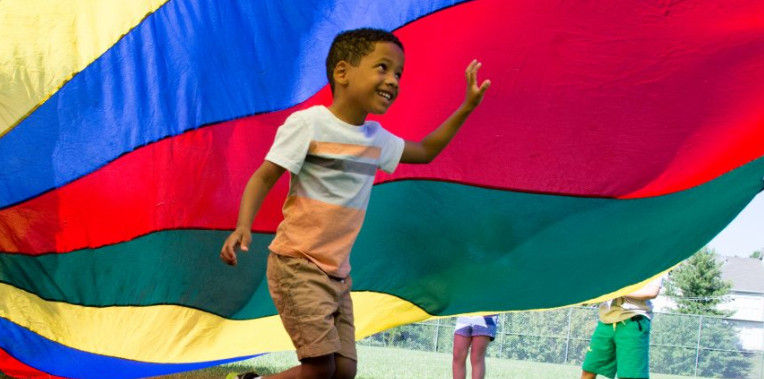 Kid playing with a colorful tarp in a winter camp