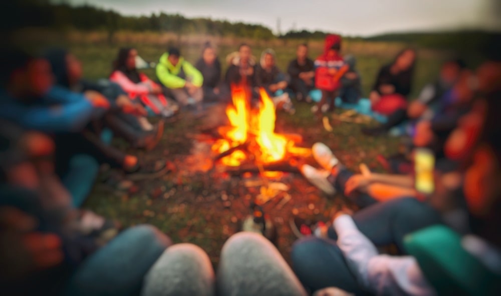 Group of friends around a campfire bonding and playing campfire games