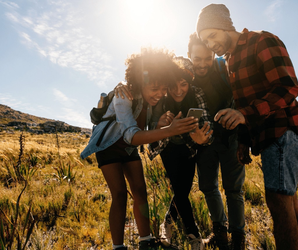 Group of hiking buddies laughing while looking at a phone