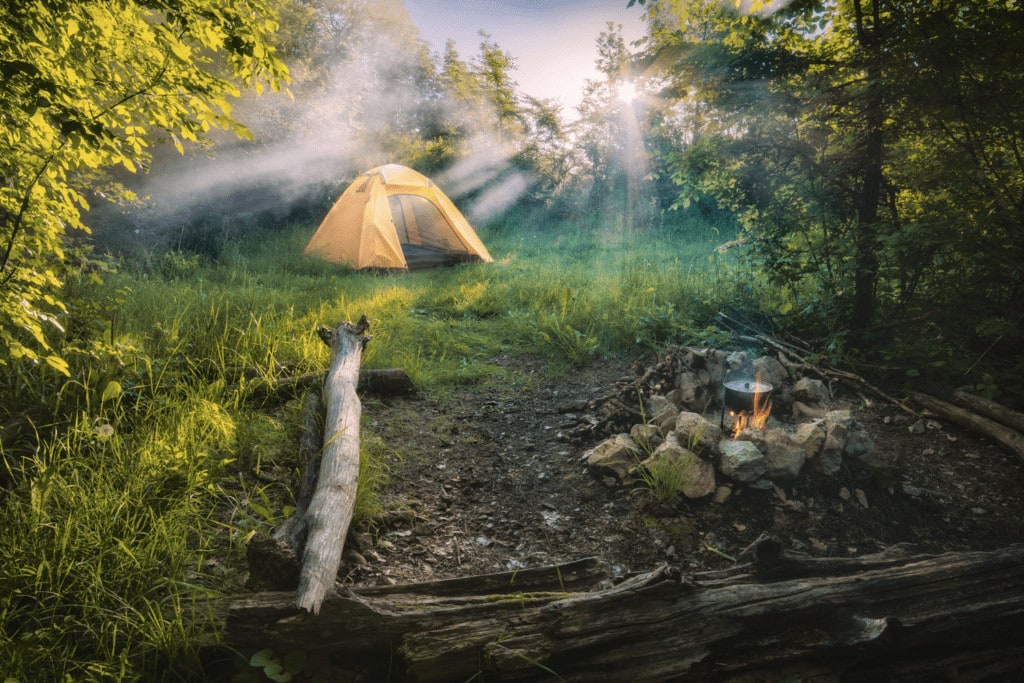 Camping tent with set up campfire while heating a pot in the forest away from bears