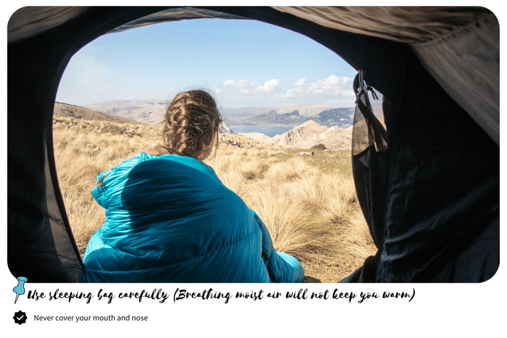Woman looking at the mountains from her tent with sleeping bag