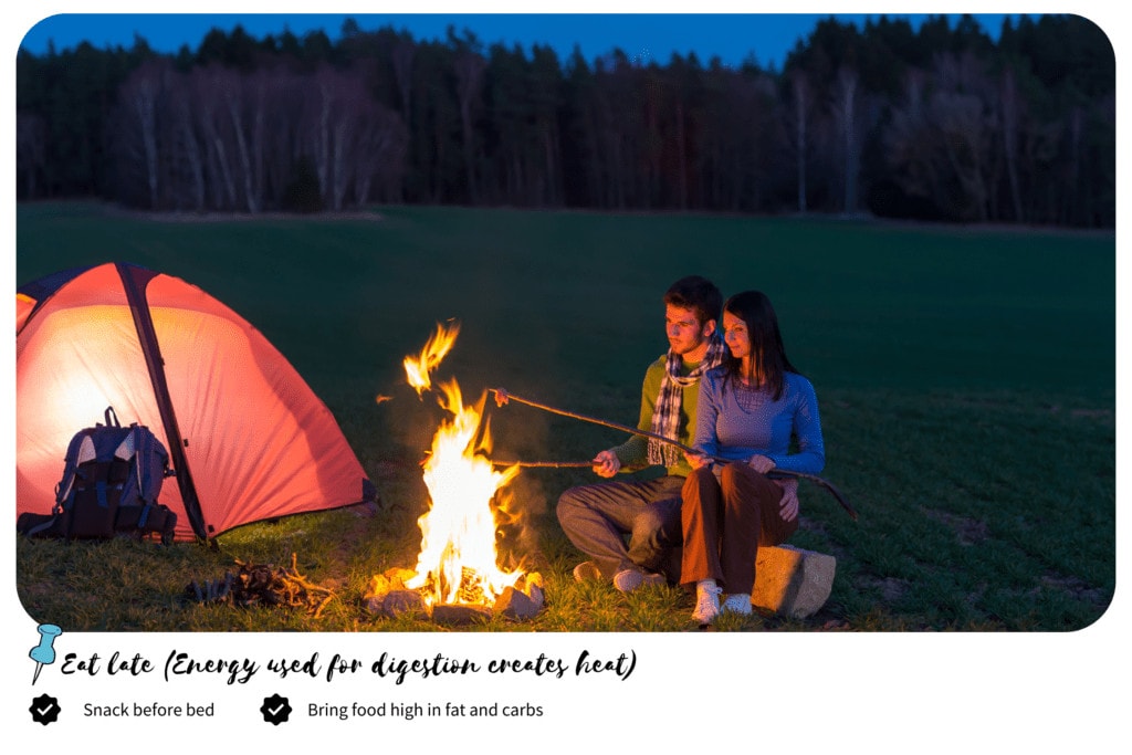 Couple cooking on a campfire with camping tent on the side
