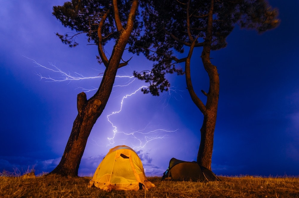 Two tents under the trees with thunderstorm in the background