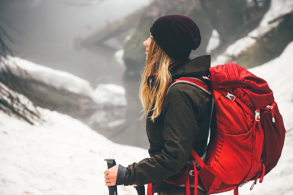 Girl hiking in winter carrying red backpack