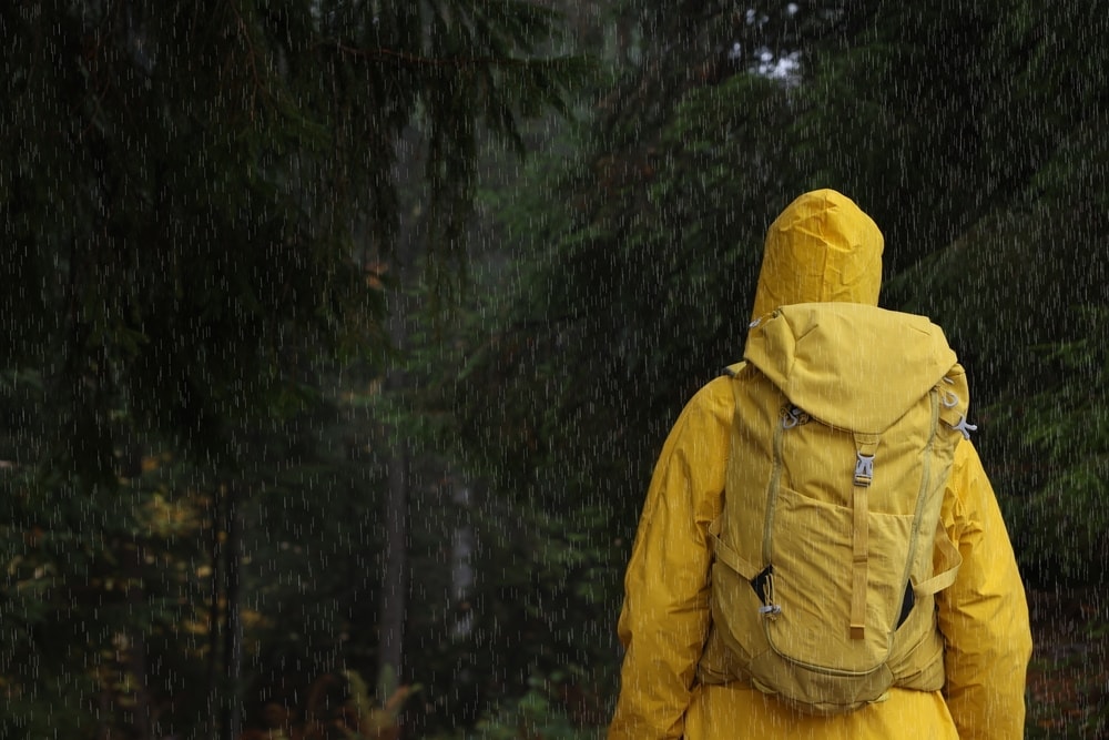 Yellow-raincoated guy with backpack standing in the rain