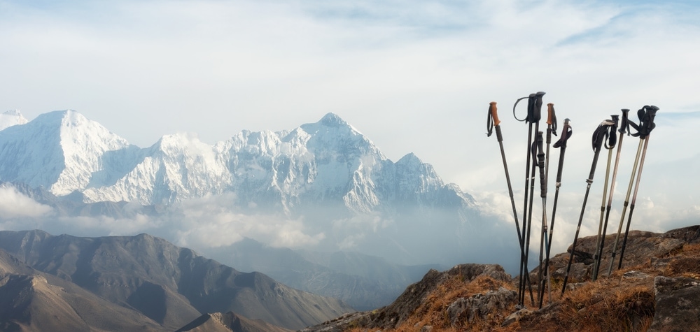 Trekking poles standing with iced mountain background