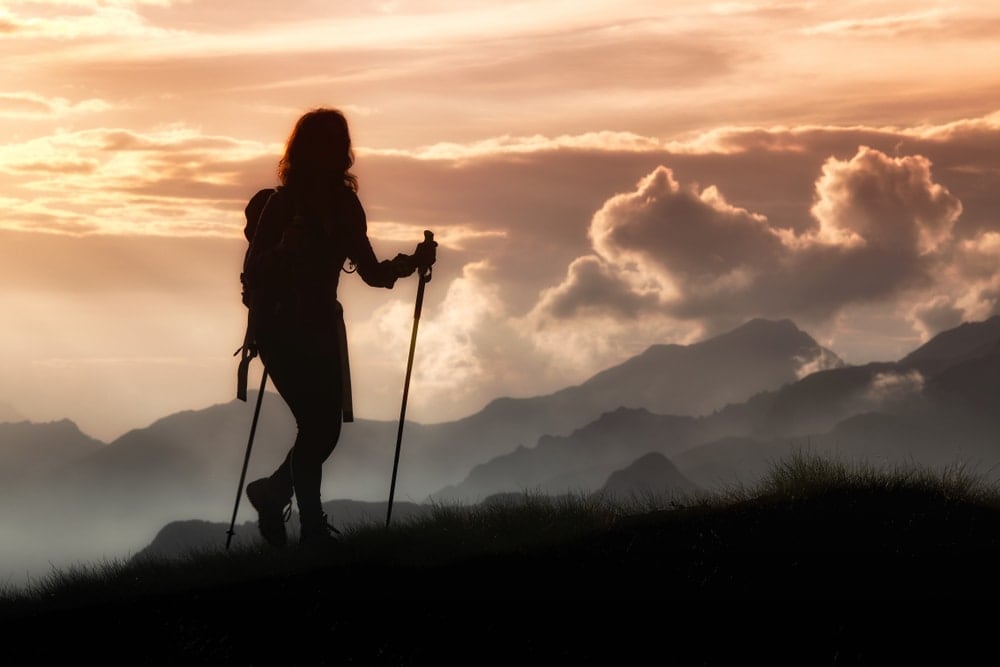 Woman trekking in silhouette using a walking poles