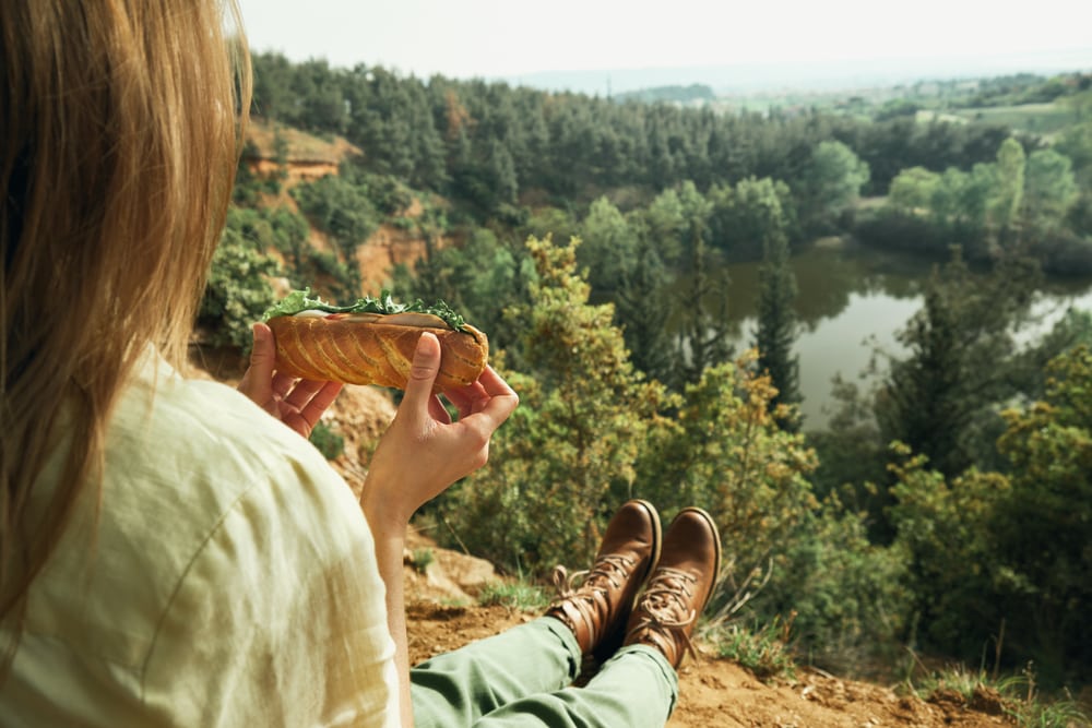 a woman eating a sandwich while hiking