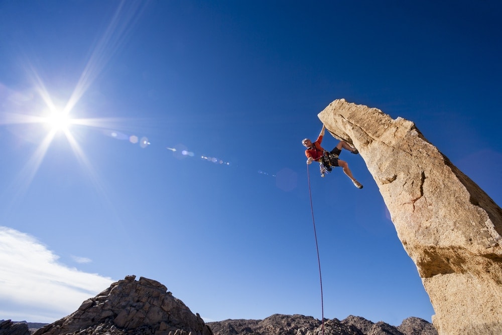 Rock climber asscends a rock spire in Joshua Tree National Park.