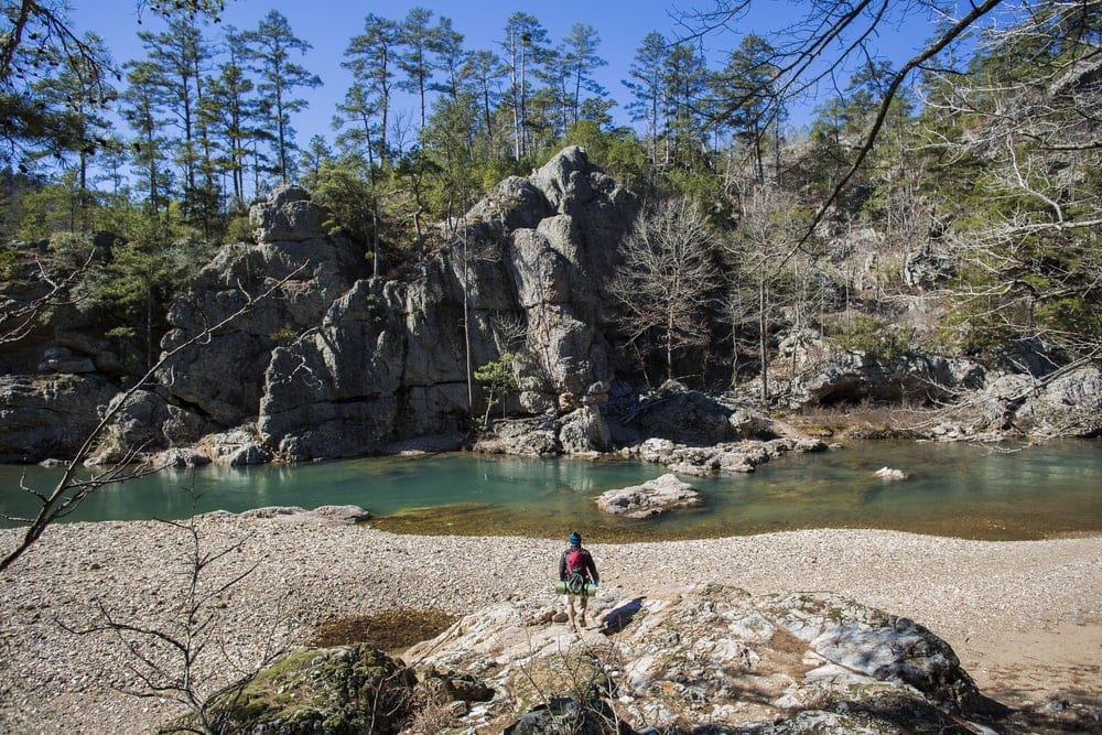 hiker and rock boulders and river in Ouachita Mouintains