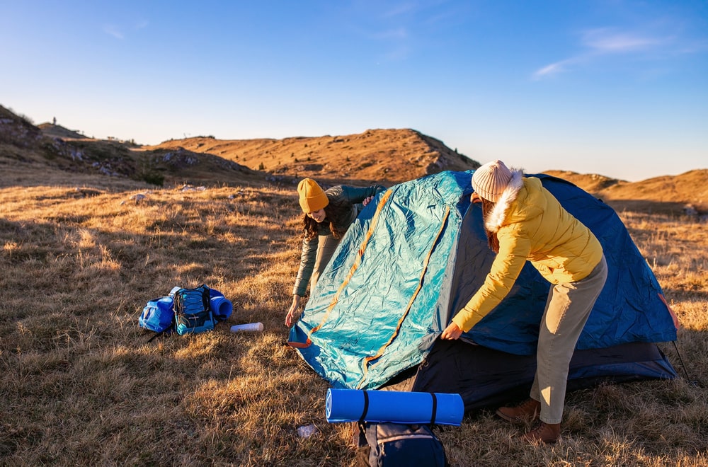 Two girls fixing their tent for their camping trip