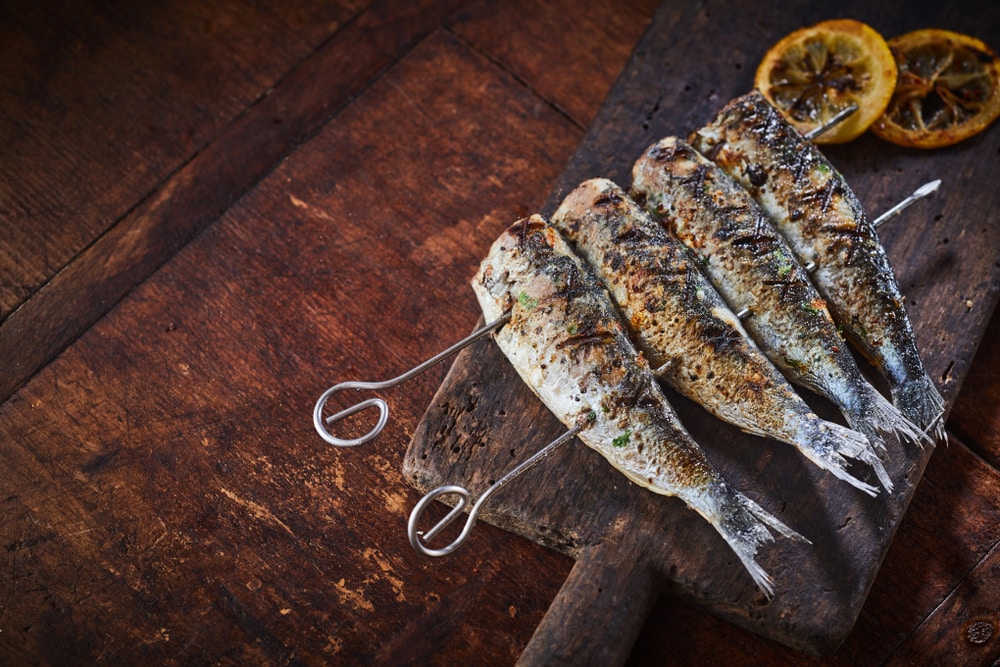 a grilled fish on a skewer on a wooden table