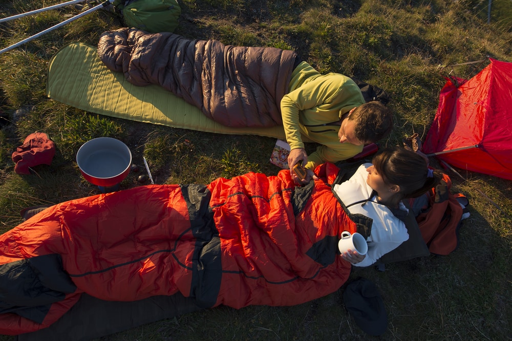 campers enjoying a morning coffee in their sleeping bags