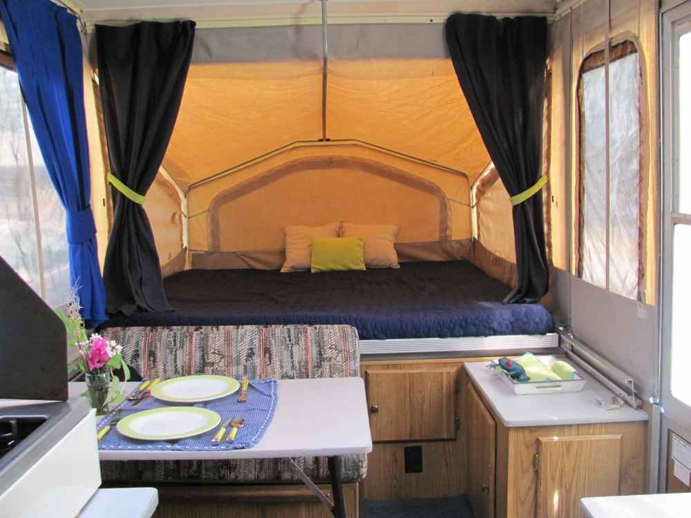 the inside of a pop up camper or tent trailer with cozy bed 