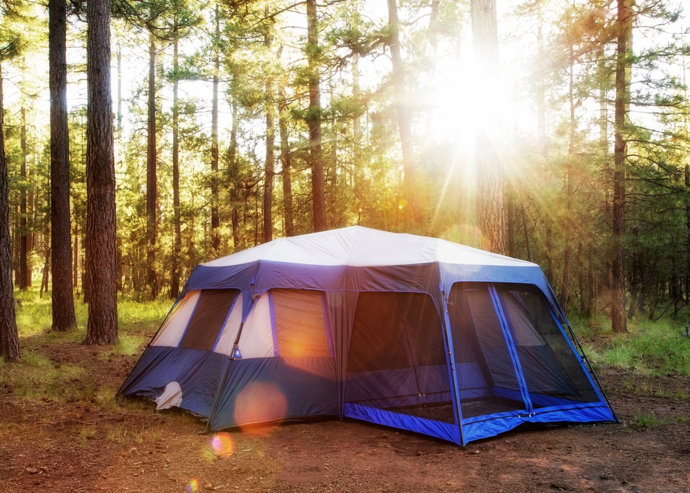 Large camping tent in the woods of Payson, Arizona at sunrise with sun flares