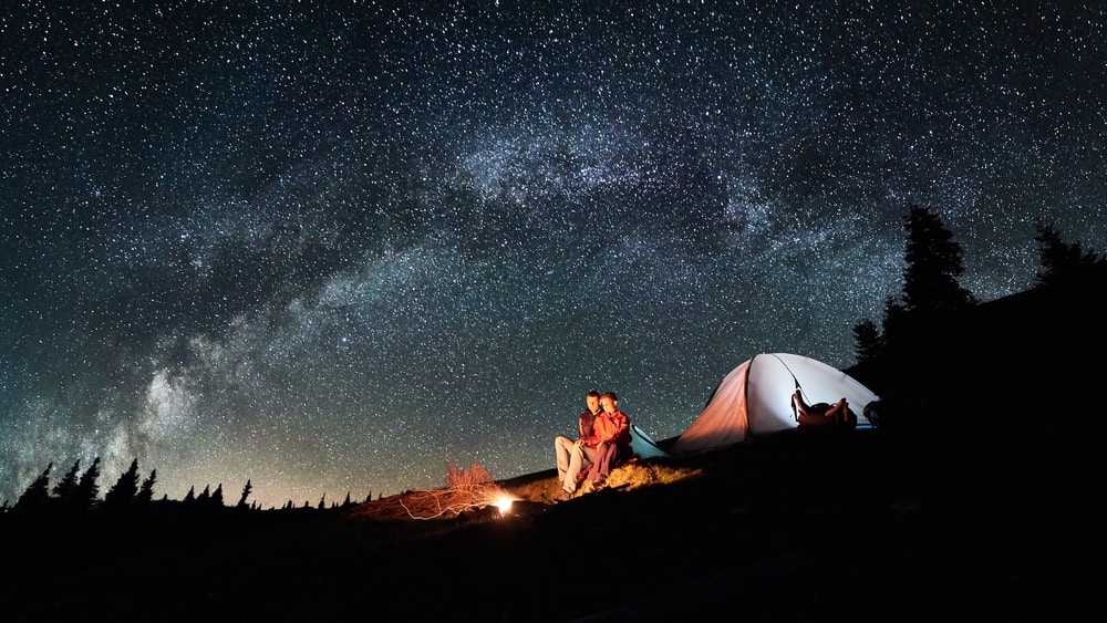 a couple camping in a under a starry night