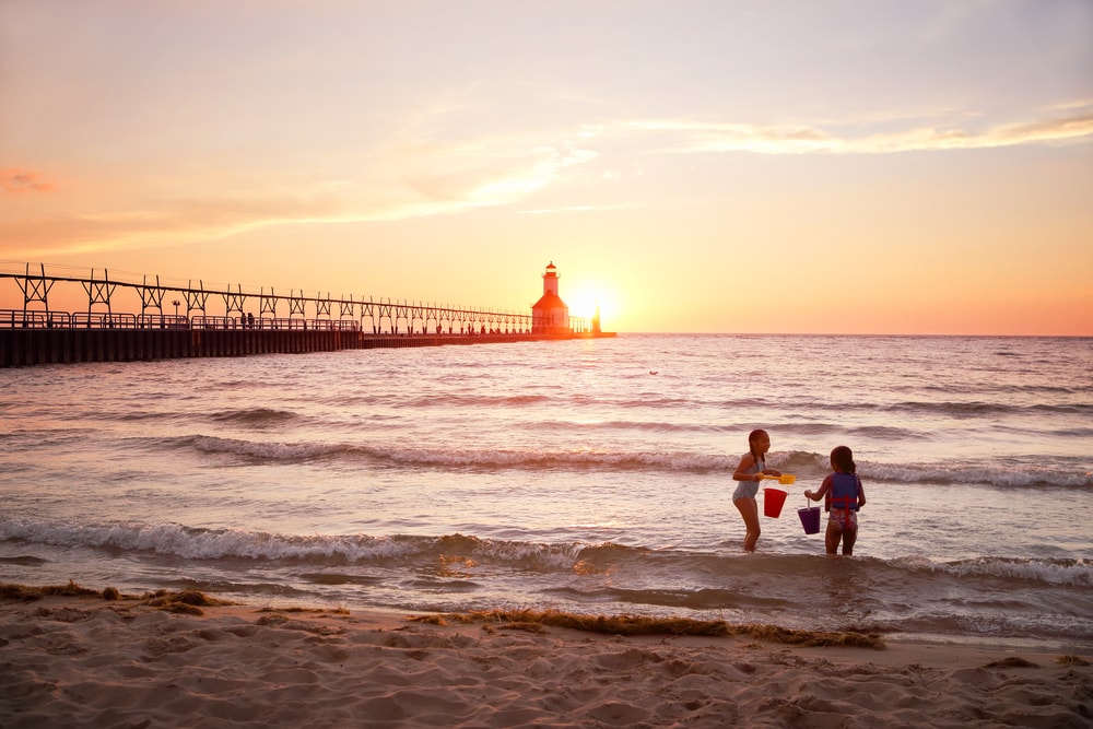 kids playing by the beach showing the St Joseph Lighthouse on Lake Michigan at sunset
