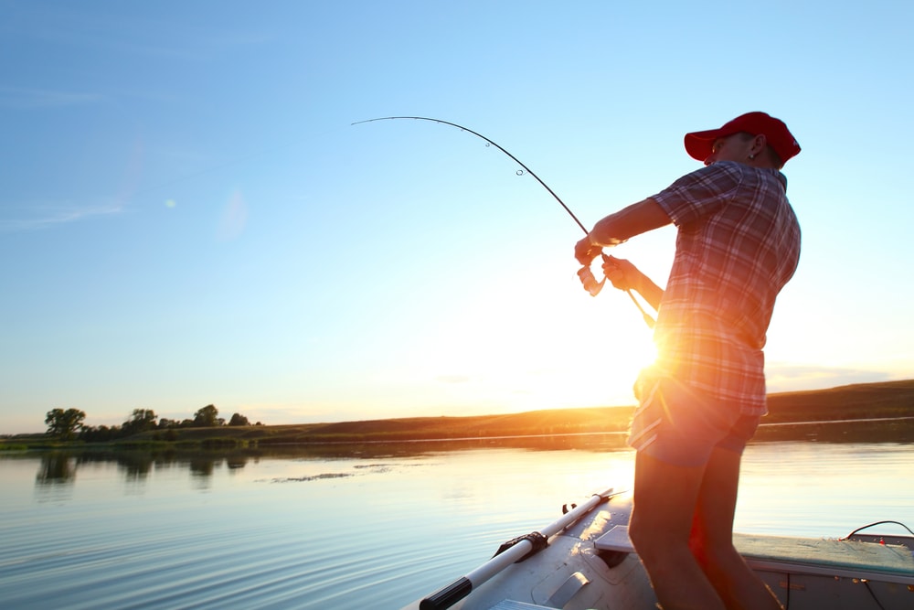 image of a young man fishing in a lake at sunset