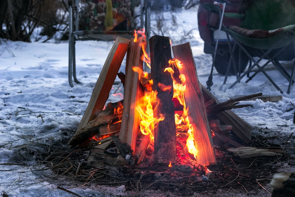 A hot burning campfire on snowy ground  at dusk