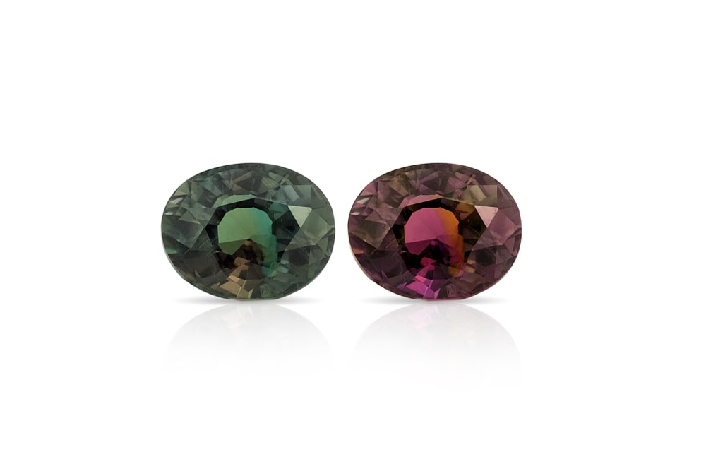 two alexandrite gems - one showing a green hue, tje other one showing a purple hue