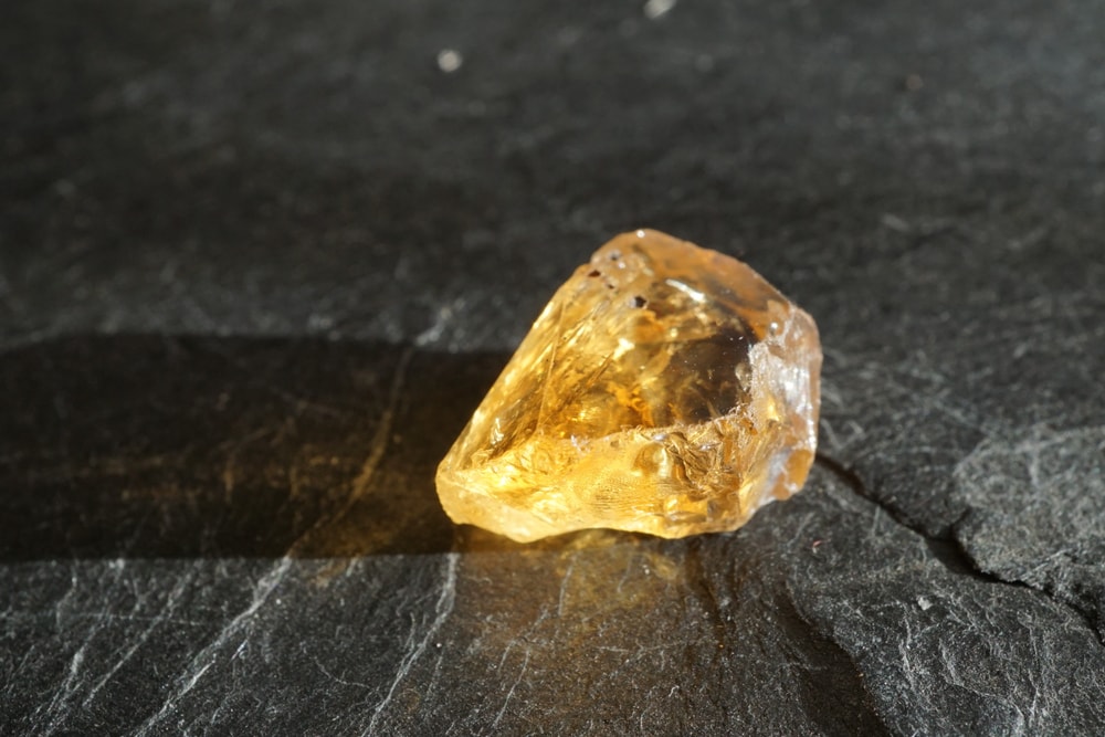 one of the semi -precious stones, a raw and uncut heat treated citrine on a a gray background