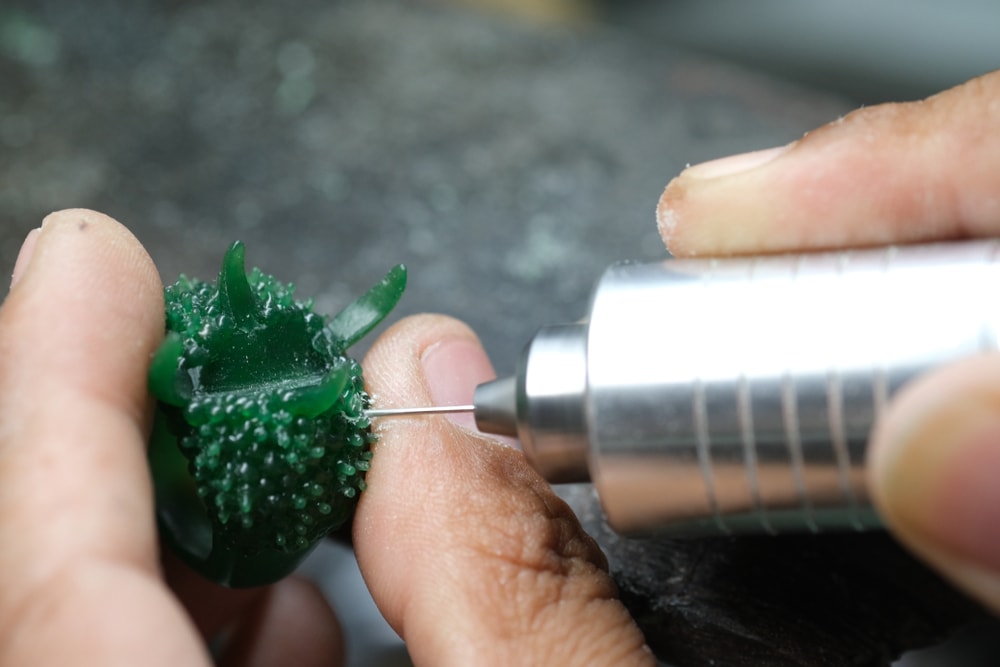  Jeweler drilling a hole for setting gemstones on a ring wax mold.