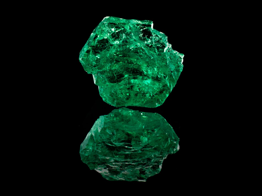 one of the most popular types of gems, is an emerald. An natural uncut emerald stone on a black background