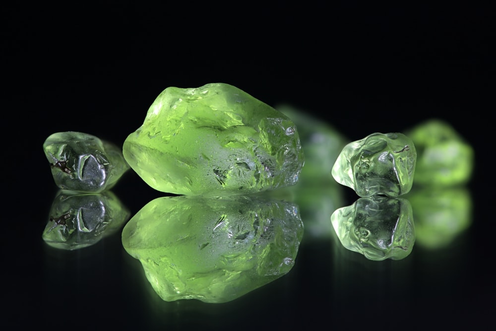 gem quality peridot crystals isolated on a black background