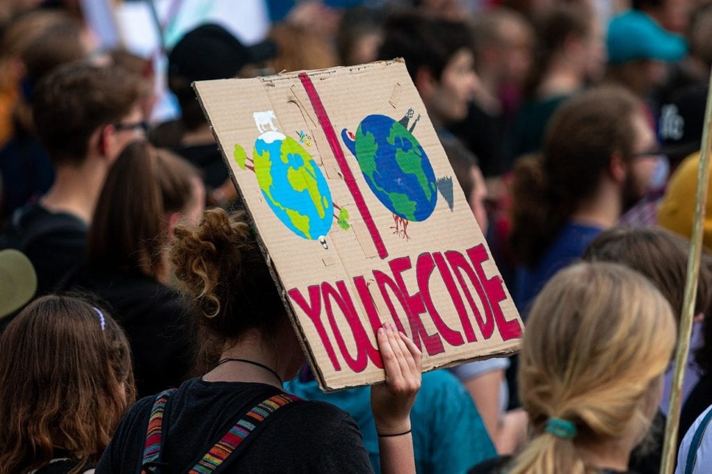 a woman holding a placard of earth during a demonstration