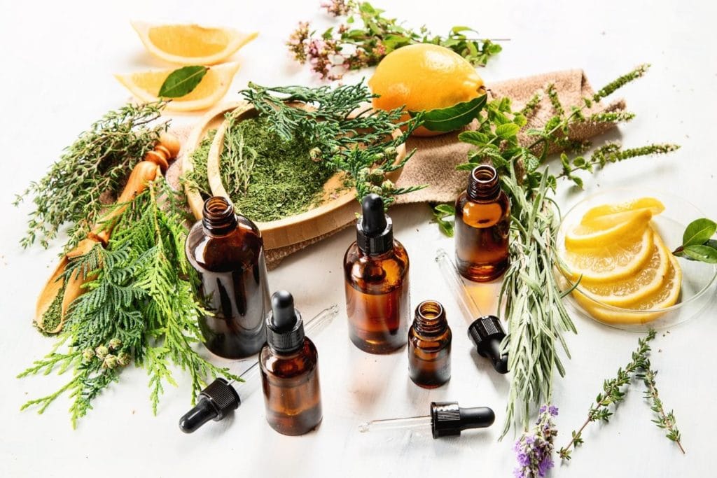 bottles of essential oils and herbs on a white background