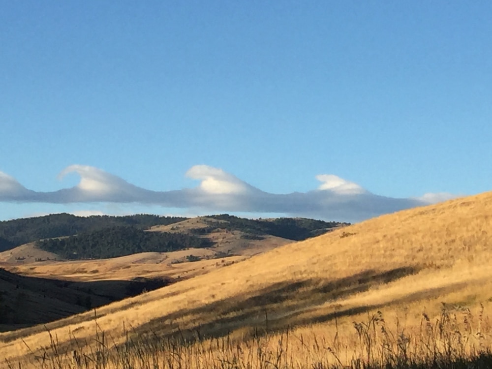 Virga clouds aligned on top of a mountain