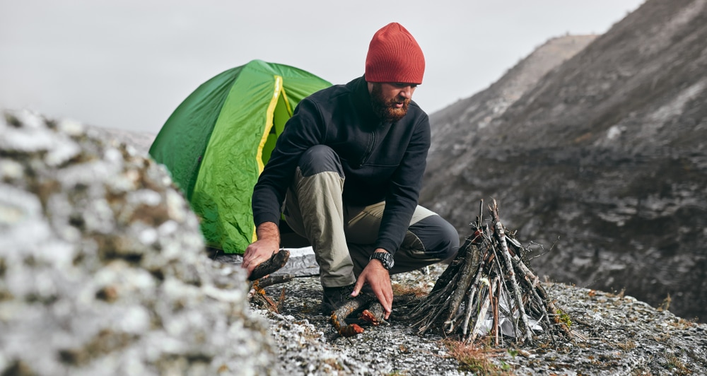 a hiker preparing to start a bonfire during winter camping