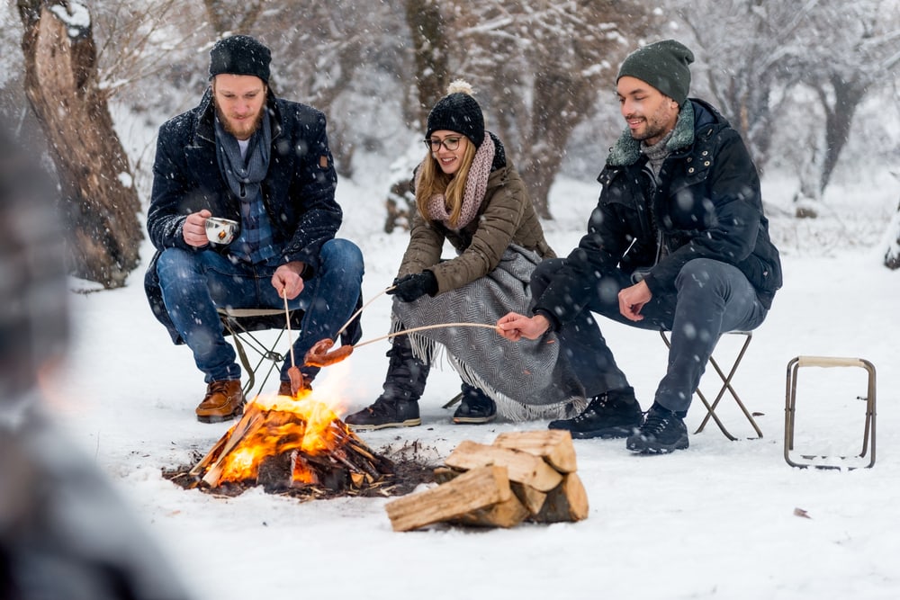 a group of friends cooking over a campfire during winter