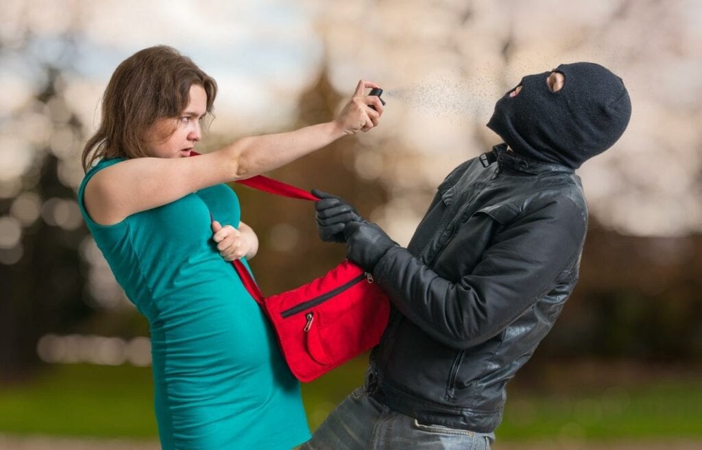 a woman using a pepper spray against a thief