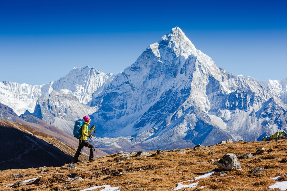 a woman hiking the Himalayas with Mount Everest in the background 