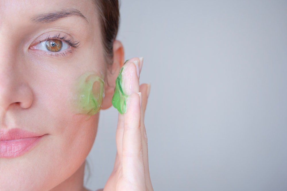 image of a woman putting a green cream on ger face 