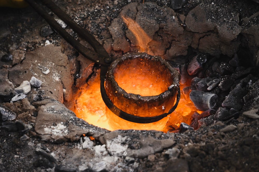 Metal being melted on a hot pit of charcoals