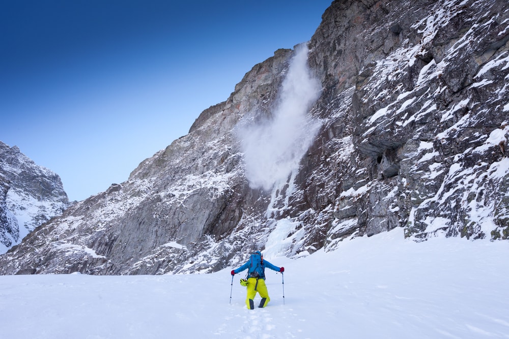 a hiker watching a small avalanche on the mountain