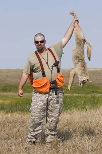 a hunter holding a killed coyote