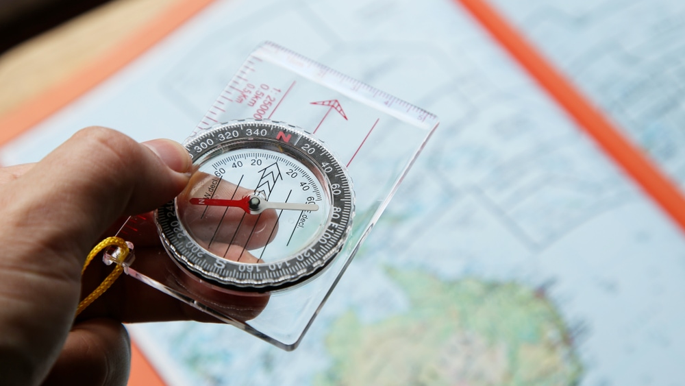 holding a base plate compass or orienteering compass over a map