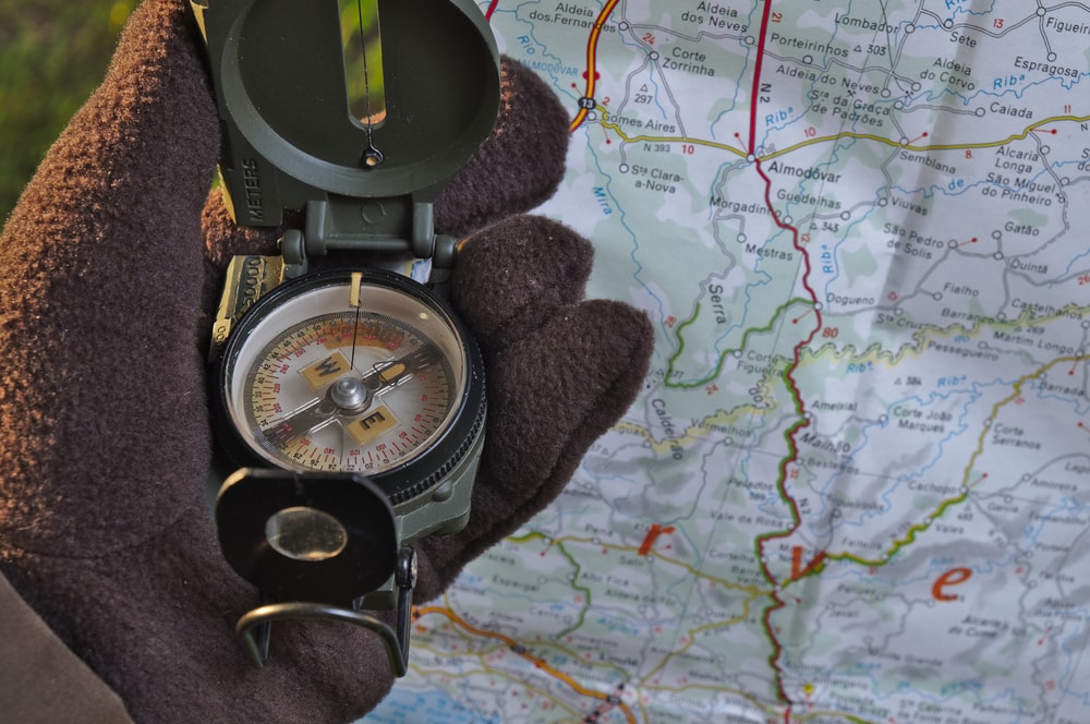 a man holding a lensatic compass or military compass with map
