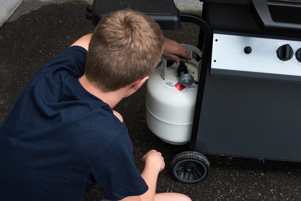 a teenager opening a propane tank for barbeque 