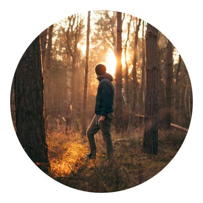 Man walking in the middle of the forest during sunset
