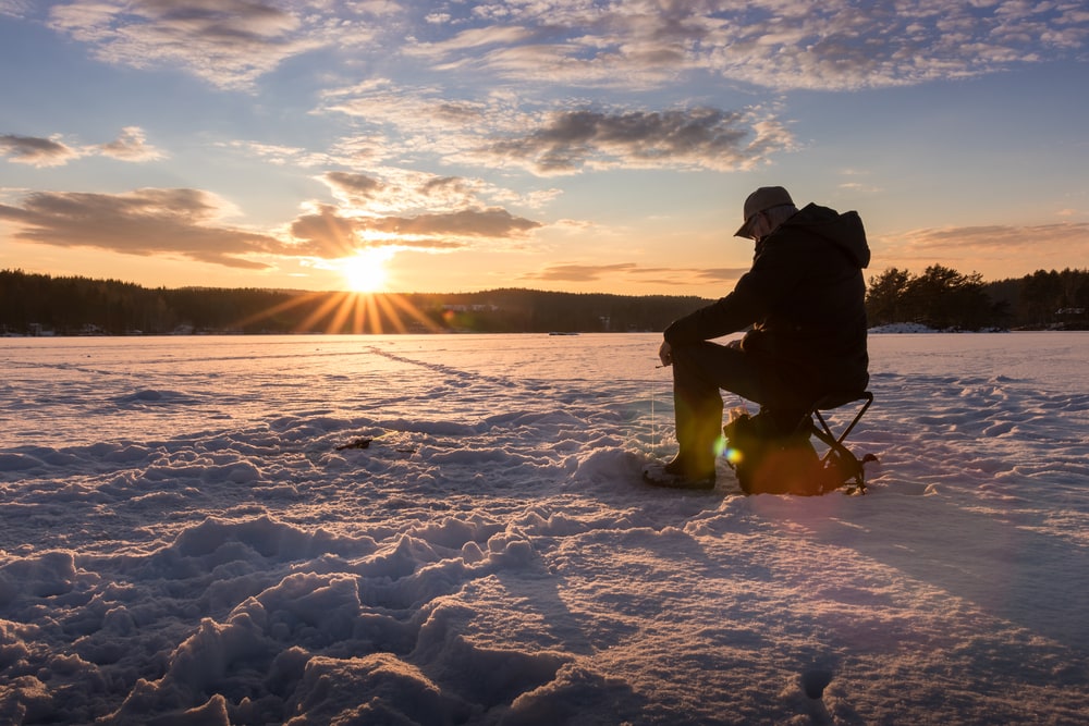Man sitting on ice waiting while fishing