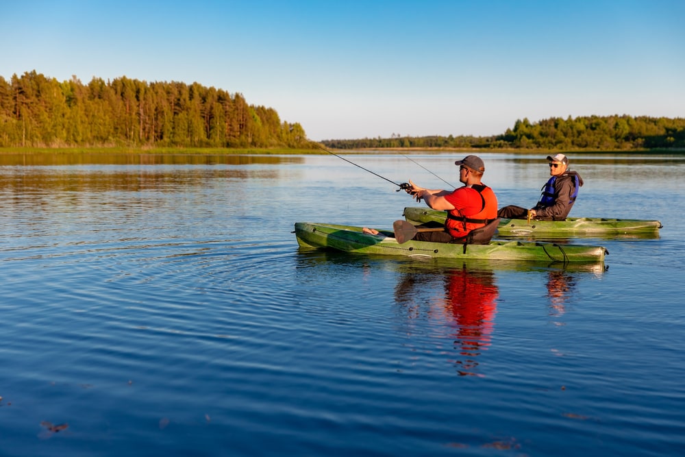 Two men doing kayak fishing on a lake