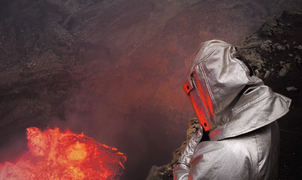 A volcanologist in a thermo-suit near a volcano crater 