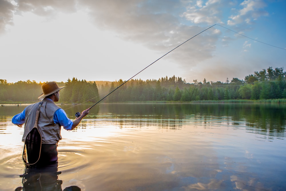 Man with a hat and net fly fishing in a pond